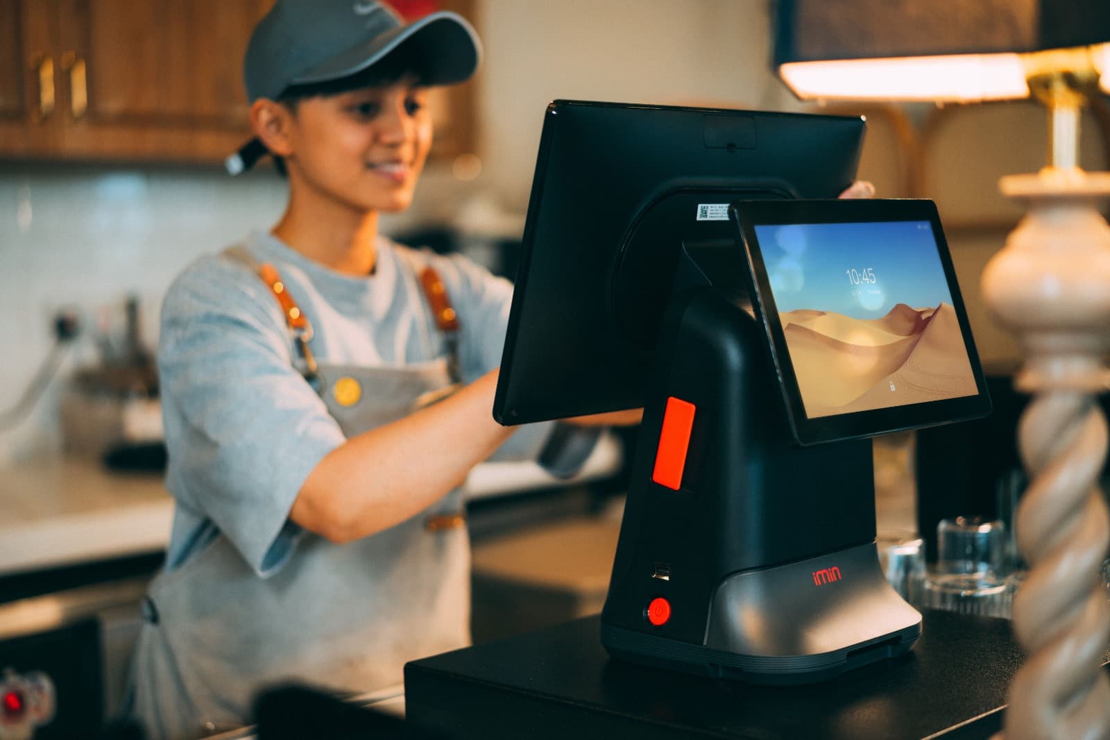Café employee operating a black iMin point-of-sale terminal